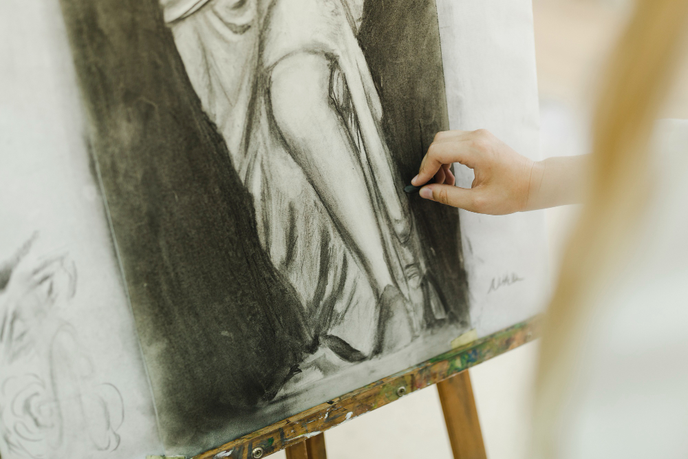 Image of student creating a charcoal portrait. 