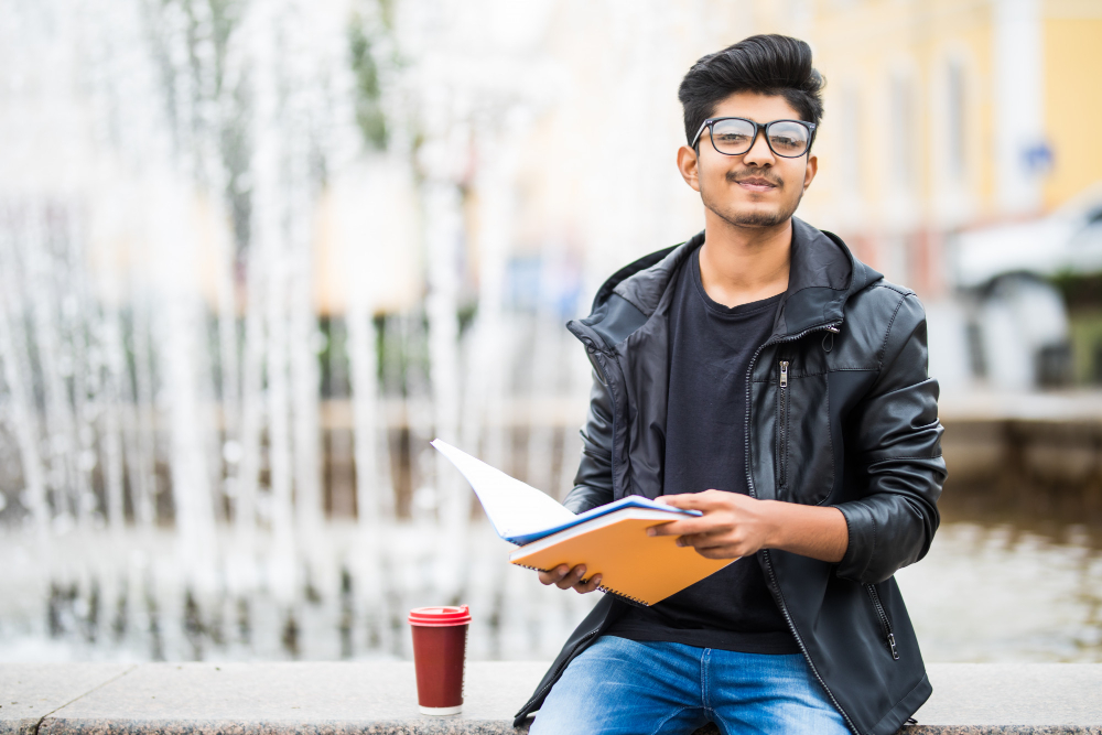 Image of student holding books in front of a fountain