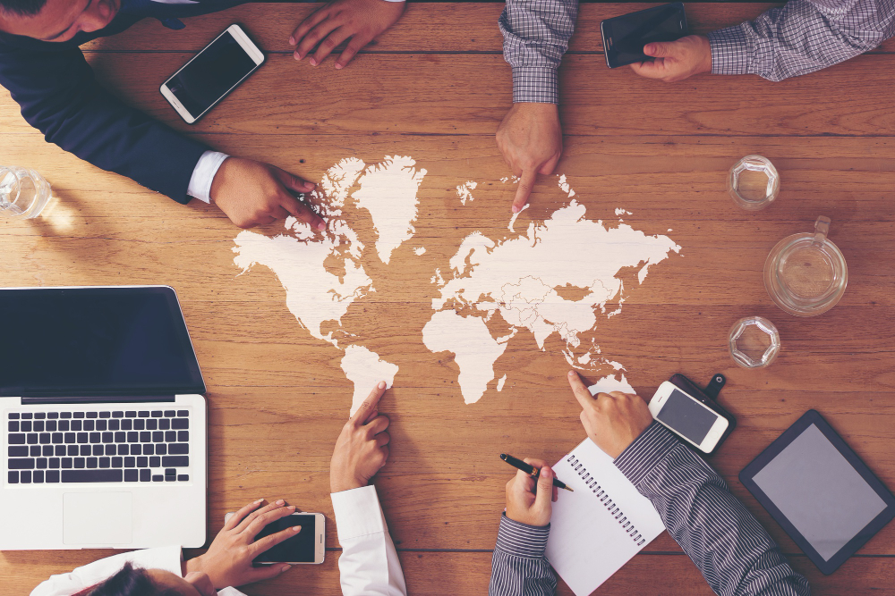 Image of business people sat around a map of the world. 