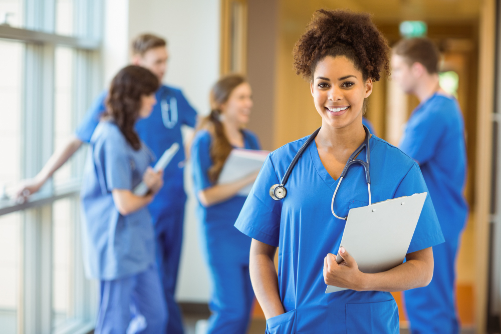 Image of a nursing student in scrubs with other students in the background.