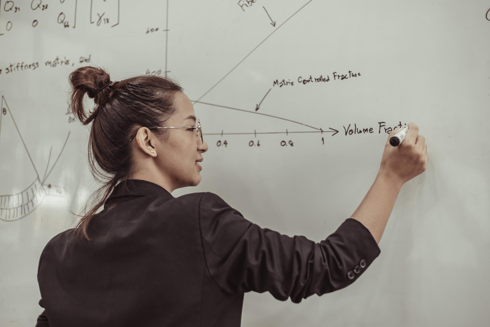 Student writing formulae and graph on whiteboard